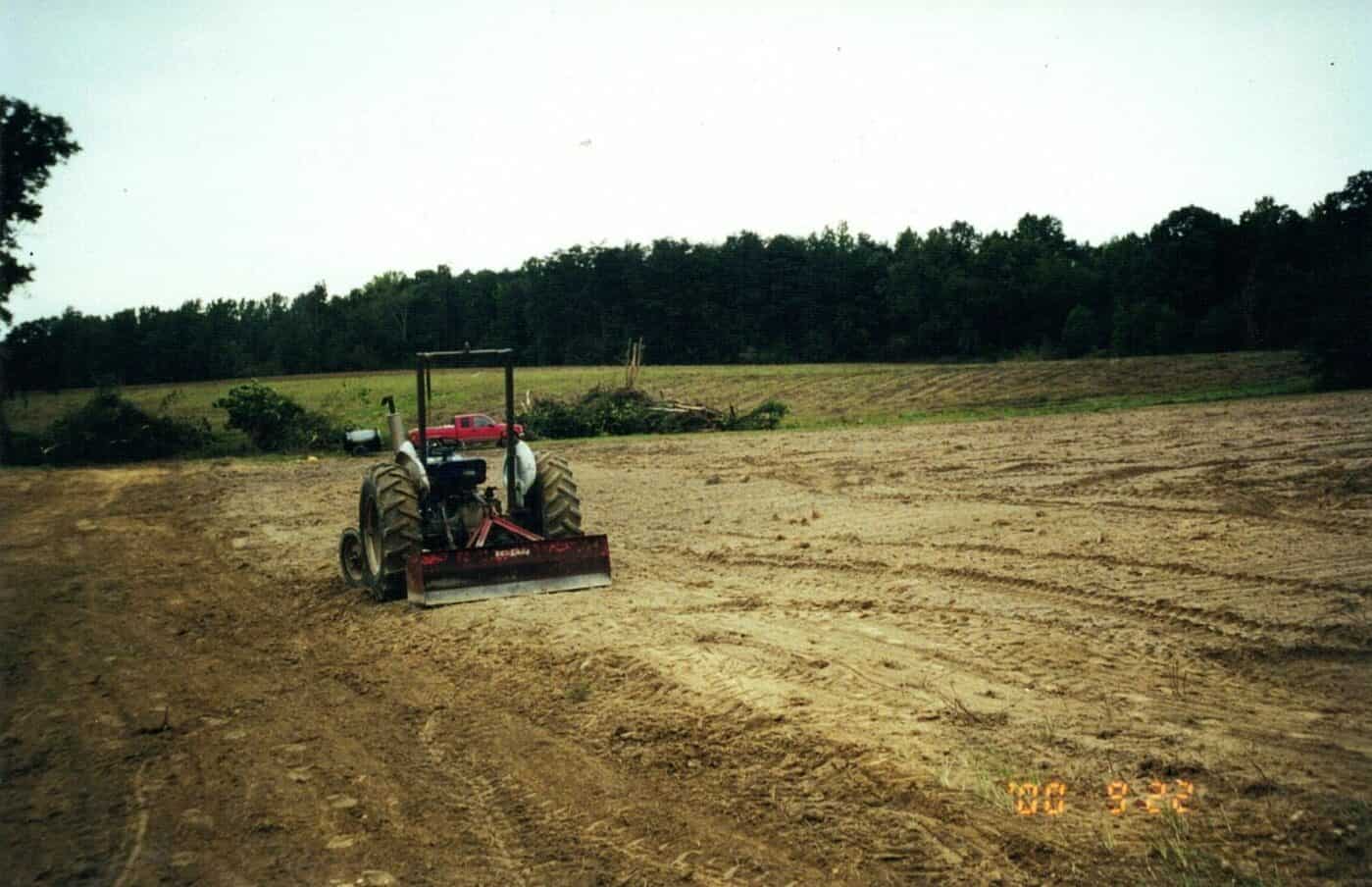 Tractor plowing field, rural farm land, daytime.