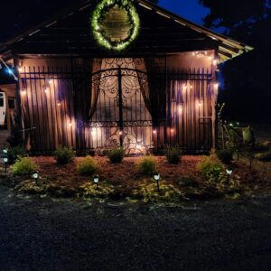 Illuminated garden shed with wreath and fairy lights at night