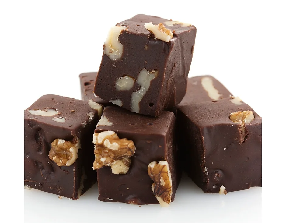Stacked chocolate fudge with walnuts on white.