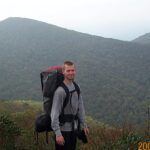 Hiker with backpack in misty mountains.