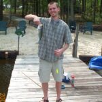 Man holding fish on lake dock outdoors