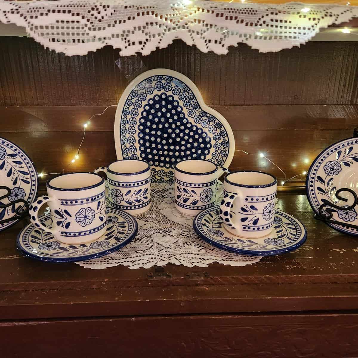 Blue and white ceramic tea set on lace tablecloth.