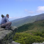 Man sitting on mountain overlook, scenic view.