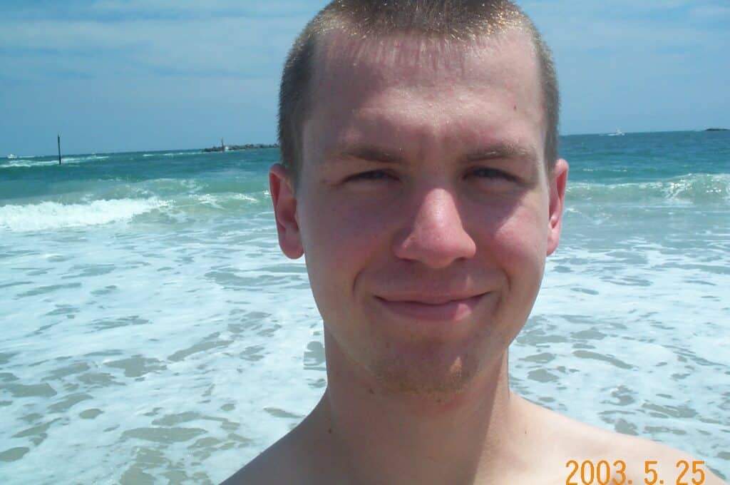 Man smiling at beach on sunny day.